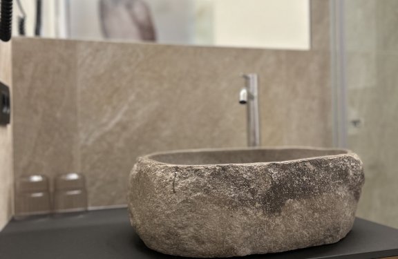 Steinwaschbecken mit silbernem Wasserhahn auf schwarzem Waschbecken-Unterschrank