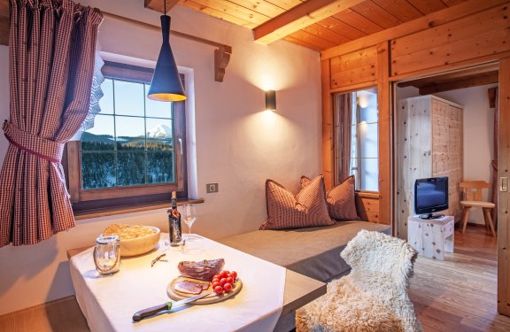 Gemütliche Sitzecke mit Tisch, TV und Fenster mit Blick auf die Berge