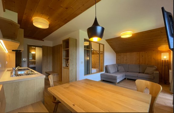 Moderne Küche mit Essbereich und grauem Sofa unter Holzbalkendecke