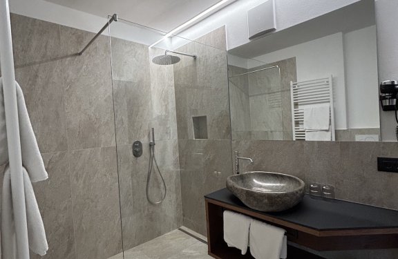 Modernes Badezimmer mit bodenloser Dusche, grauen Fliesen und Waschbecken
