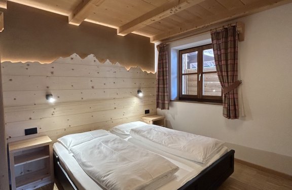 Gemütliches Schlafzimmer mit Doppelbett, Holzdecke und Fenster mit Tageslicht