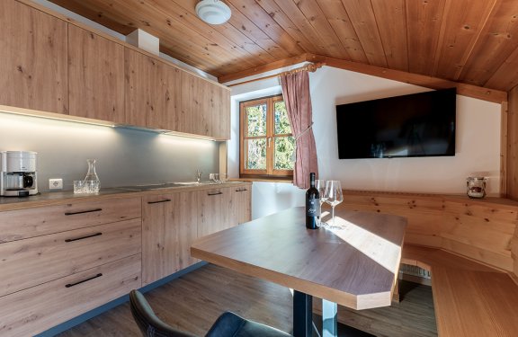 Moderne Küchenzeile mit Holzschränken und Esstisch mit Flasche Wein