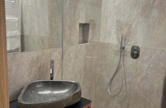Moderne Dusche mit Naturstein-Waschbecken und Handtüchern