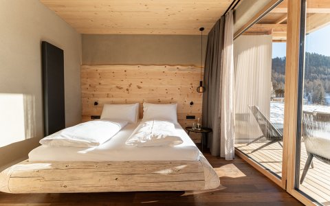 Bright bedroom with wooden bed, large window, and snowy landscape view outside