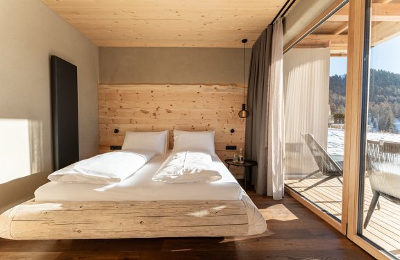 Bright bedroom with wooden bed, large window, and snowy landscape view outside