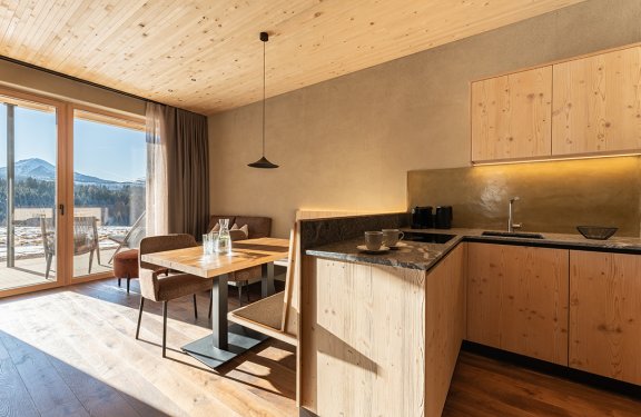 Bright kitchen with wooden cabinets and dining table next to large windows showing mountain view