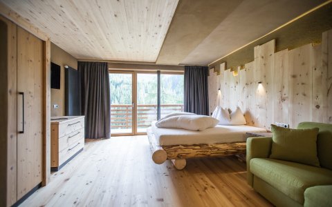 Gemütliches Schlafzimmer mit Holzdecke, Holzbett und grünem Sofa