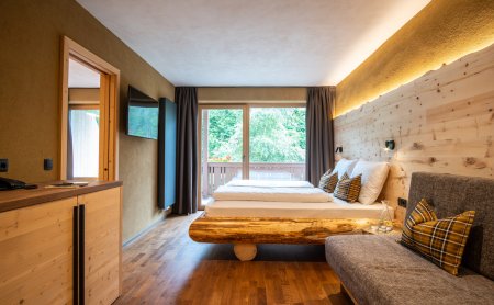 Camera con mobili in legno, letto grande, divano e vista sul balcone