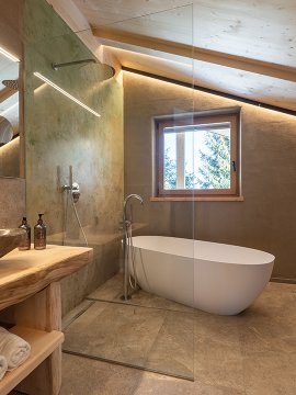 Modernes Badezimmer mit freistehender Badewanne, Steinwaschbecken und Holzdecke unter Dachschräge
