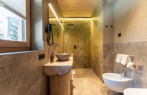Modern bathroom with wooden sink, glass shower enclosure, and window on the left