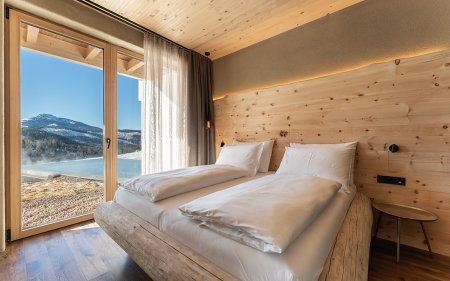 Modernes Schlafzimmer mit Holzwänden und großem Fenster mit Bergblick